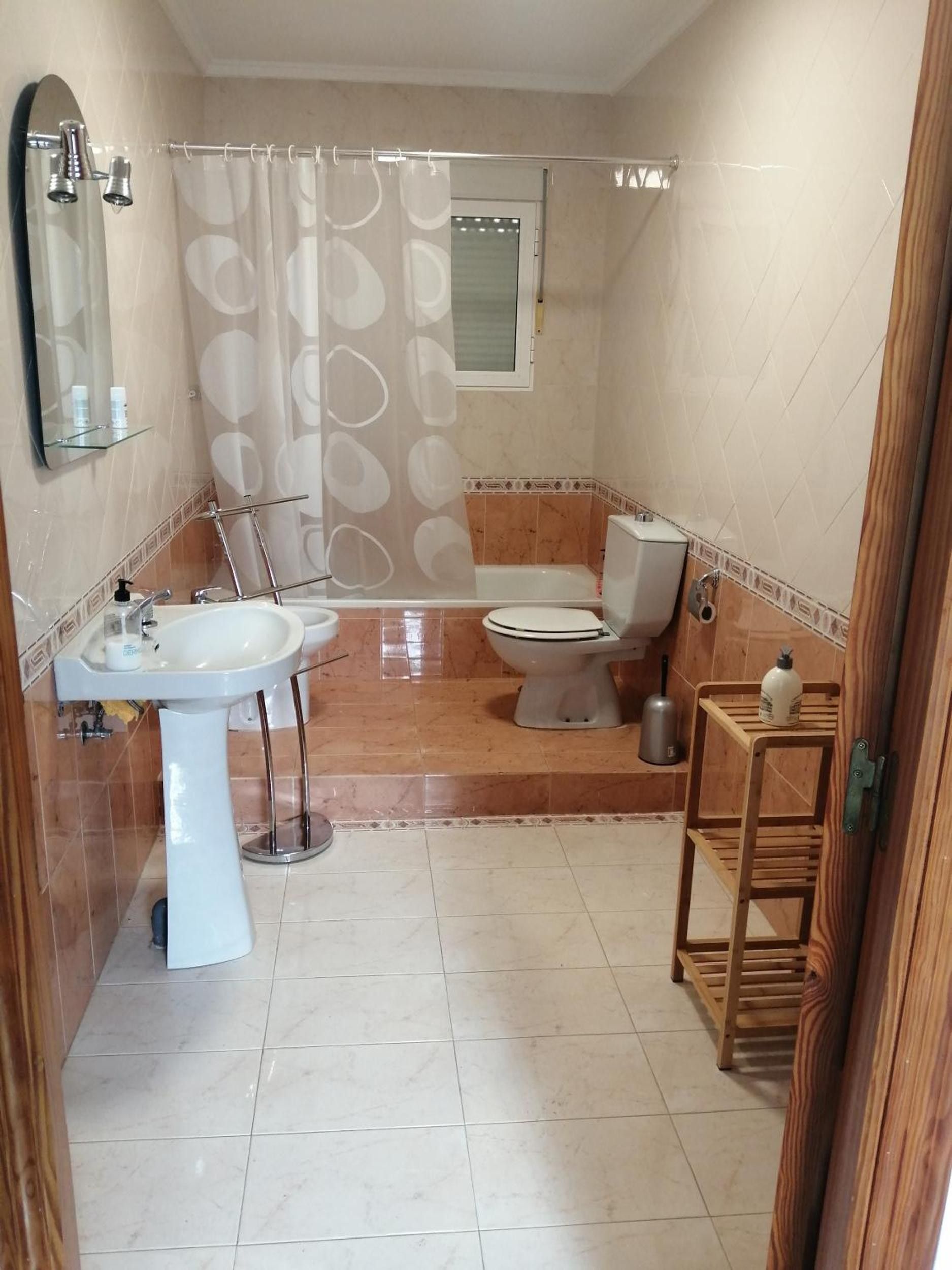 Un baño con lavamanos pedestal, inodoro y zona de ducha.