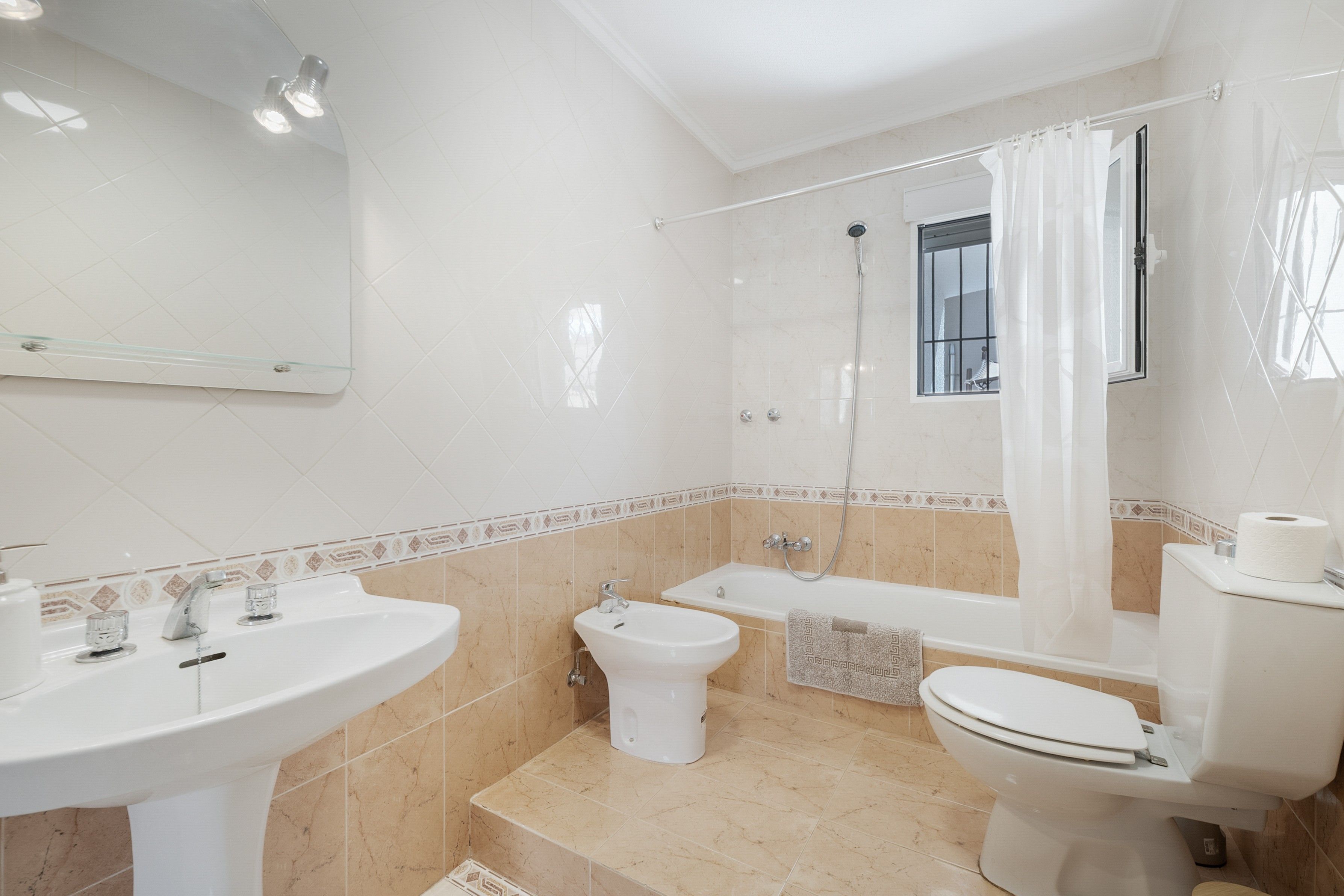 Een badkamer met een wastafel, toilet, badkuip en douchegordijn.
