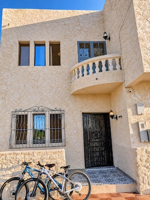 A building with a textured facade, a black door, and a balcony with a railing. - Luxurious 5-bedroom house in quaint Sidi Kaouki  150m walk from the beach (Sidi Kaouki)