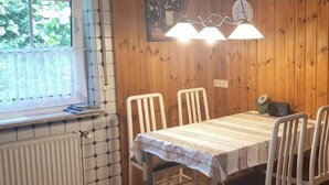 A wooden-paneled room with a table and chairs, a window with a view, and a clock on the wall. - Holiday Apartment in Eggstedt With Terrace (Eggstedt)