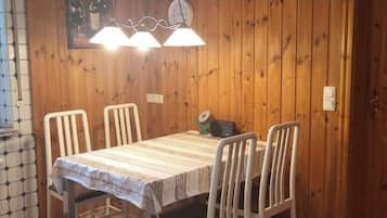 Una habitación con paneles de madera, una mesa, sillas, una ventana con vistas y un reloj en la pared.