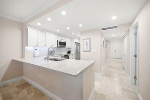 Une cuisine moderne avec des meubles blancs, un réfrigérateur en acier inoxydable et un four à micro-ondes.