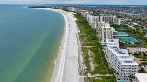 A coastal cityscape with a beach, high-rise buildings, and a clear view of the ocean. - Beachfront Condo on Marco Island. Resort style amenities..3 bed, two full bath! (Marco Island)