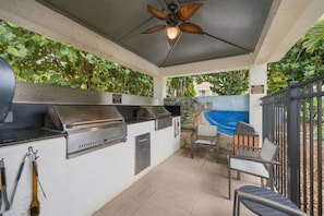 An outdoor kitchen area with a grill, bar tools, and a ceiling fan. - Beachfront Condo on Marco Island. Resort style amenities..3 bed, two full bath! (Marco Island)