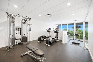 A gym with cardio machines, weightlifting equipment, and a bench. - Beachfront Condo on Marco Island. Resort style amenities..3 bed, two full bath! (Marco Island)