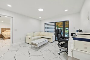 A modern bedroom with a bed, a sofa, a desk, and a printer. - Modern Waterfront Retreat Oversize outdoor Tiki, kitchen and heated SPA (Fort Lauderdale)