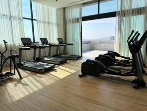 Ein Fitnessraum mit Laufbändern, Crosstrainern und Rudergeräten.