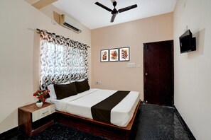A bedroom with a bed, a nightstand, a wall-mounted TV, an air conditioning unit, and a ceiling fan. - Super Collection O Kammasandra Gate (Bengaluru)