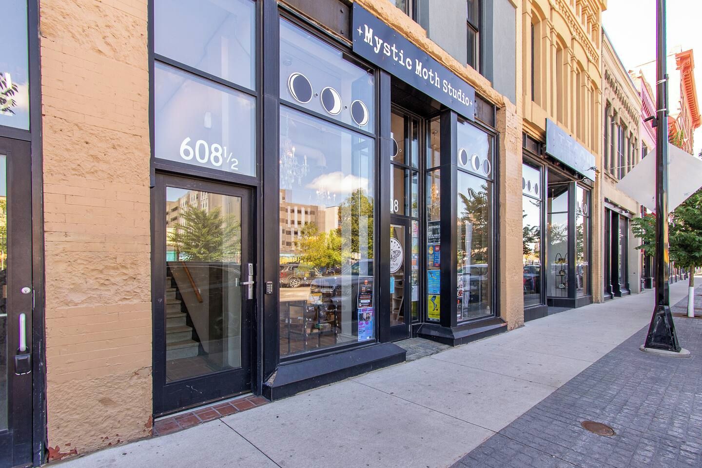 En bygning med store glasruder og et skilt, der viser 'Mystic Moth Studio'.