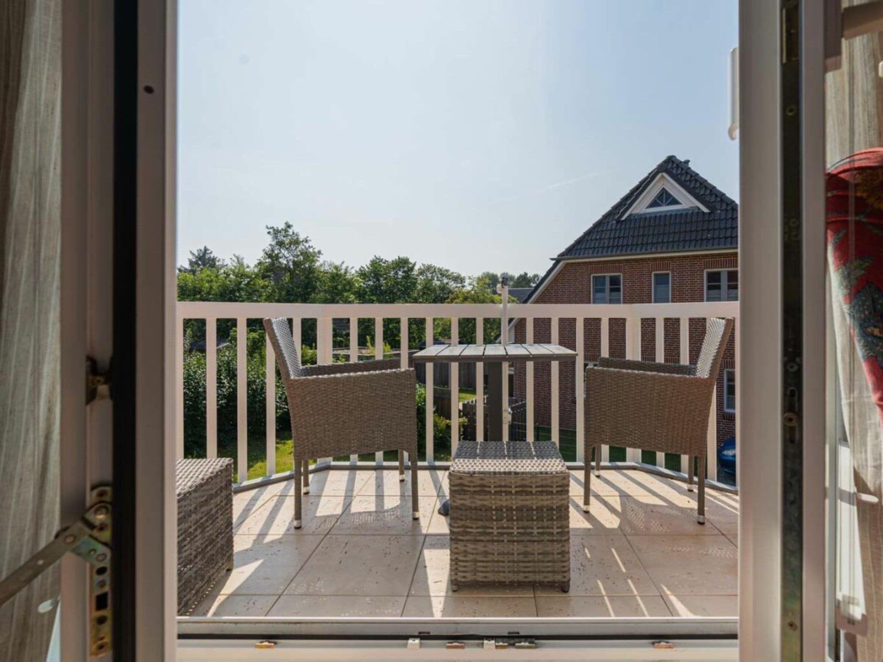 A balcony with wicker furniture and a view of a residential building.