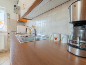 A kitchen with a stainless steel sink, wooden countertop, and a coffee maker. - Holiday Apartment 4 "muller" (St. Peter-Ording)