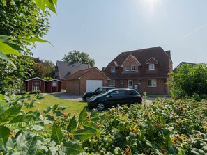 A residential property with a large brick house, a garage, and a car parked in the driveway. - Holiday Apartment 4 "muller" (St. Peter-Ording)