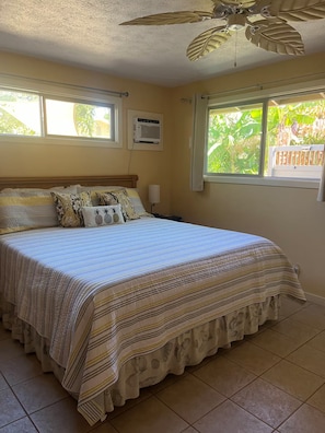 A bedroom with a bed, two windows, an air conditioning unit, and a ceiling fan. - Hale Manu i ke Kai (Kihei)