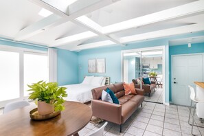 A modern room with a bed, sofa, and dining table, featuring a large window and a view into the kitchen. - Private Guesthouse Near Beach & Downtown (St. Petersburg)