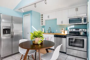 A modern kitchen with stainless steel appliances, a round wooden table, and white chairs. - Private Guesthouse Near Beach & Downtown (St. Petersburg)