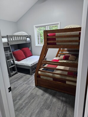 Une chambre avec un lit superposé, une échelle et une fenêtre donnant sur les arbres.
