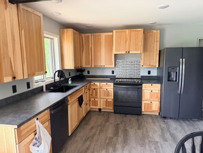 Eine moderne Küche mit Holzausstattung, einem schwarzen Kühlschrank und einem Edelstahlbackofen.