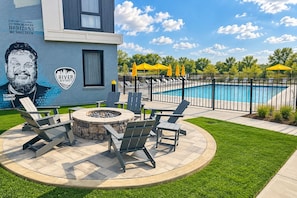 A poolside area with a fire pit and lounge chairs, a mural, and a swimming pool. - Pool, Hot Tub, Sauna, 11 Beds, Rooftop Kitchen (Nashville)