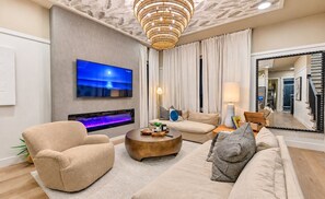 Una sala moderna con televisor de pantalla plana, chimenea, sofá, mesa de centro y un espejo grande.