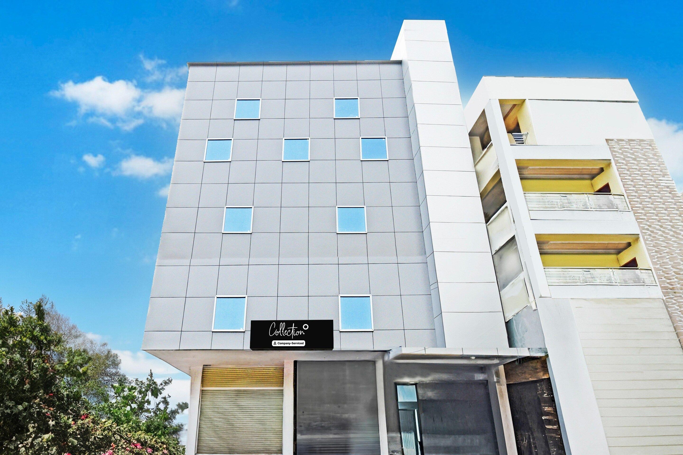 A modern building with a grey facade, multiple windows, and a sign indicating a company-serviced collection.