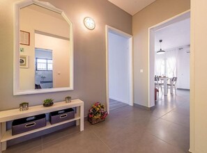A hallway with a large mirror, a bench with storage, a small plant, and a basket of flowers. - Three Bedroom Apartment with Balcony (Rogoznica)