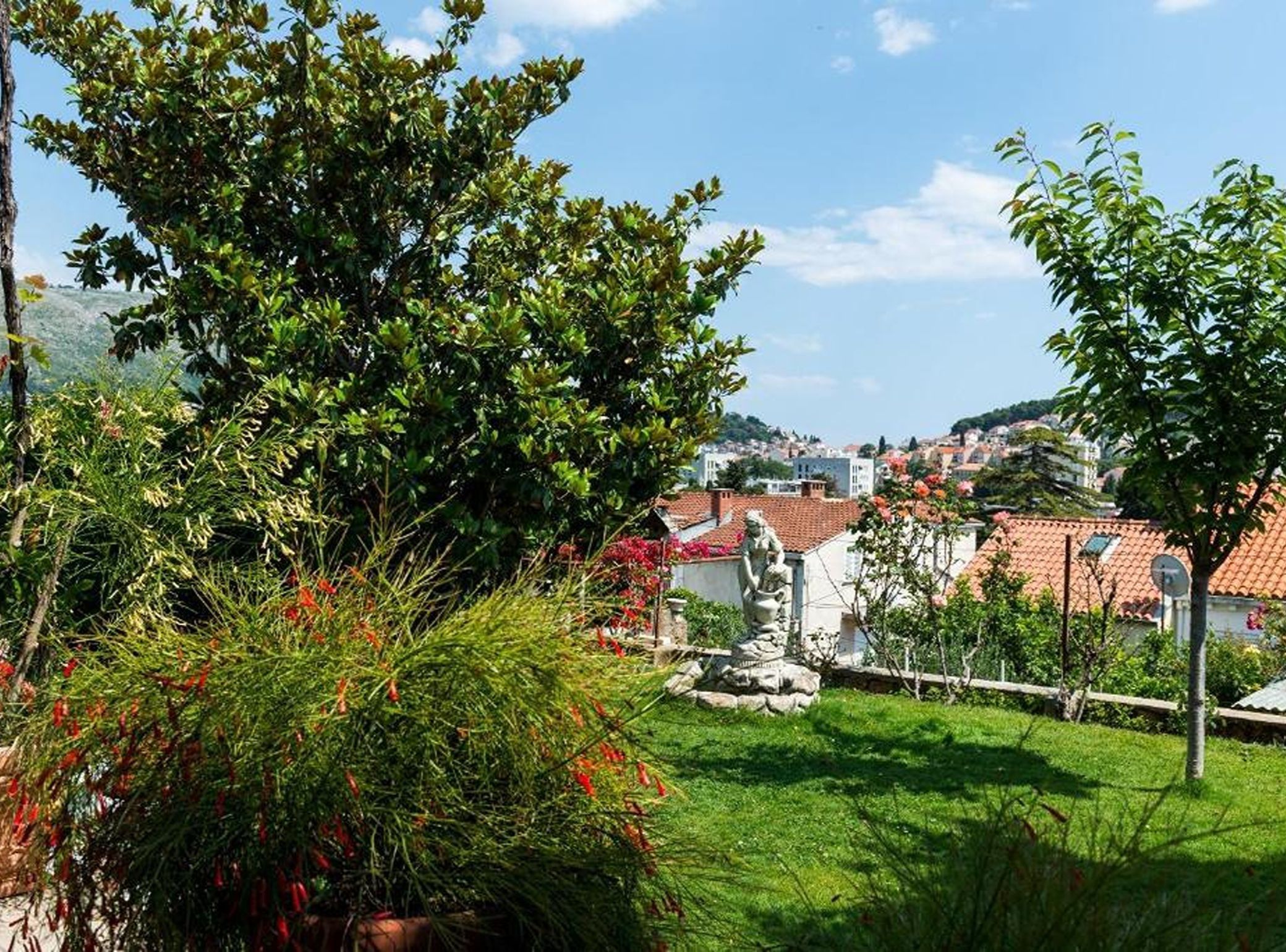 A residential area with a clear view of houses, a statue, and lush greenery.