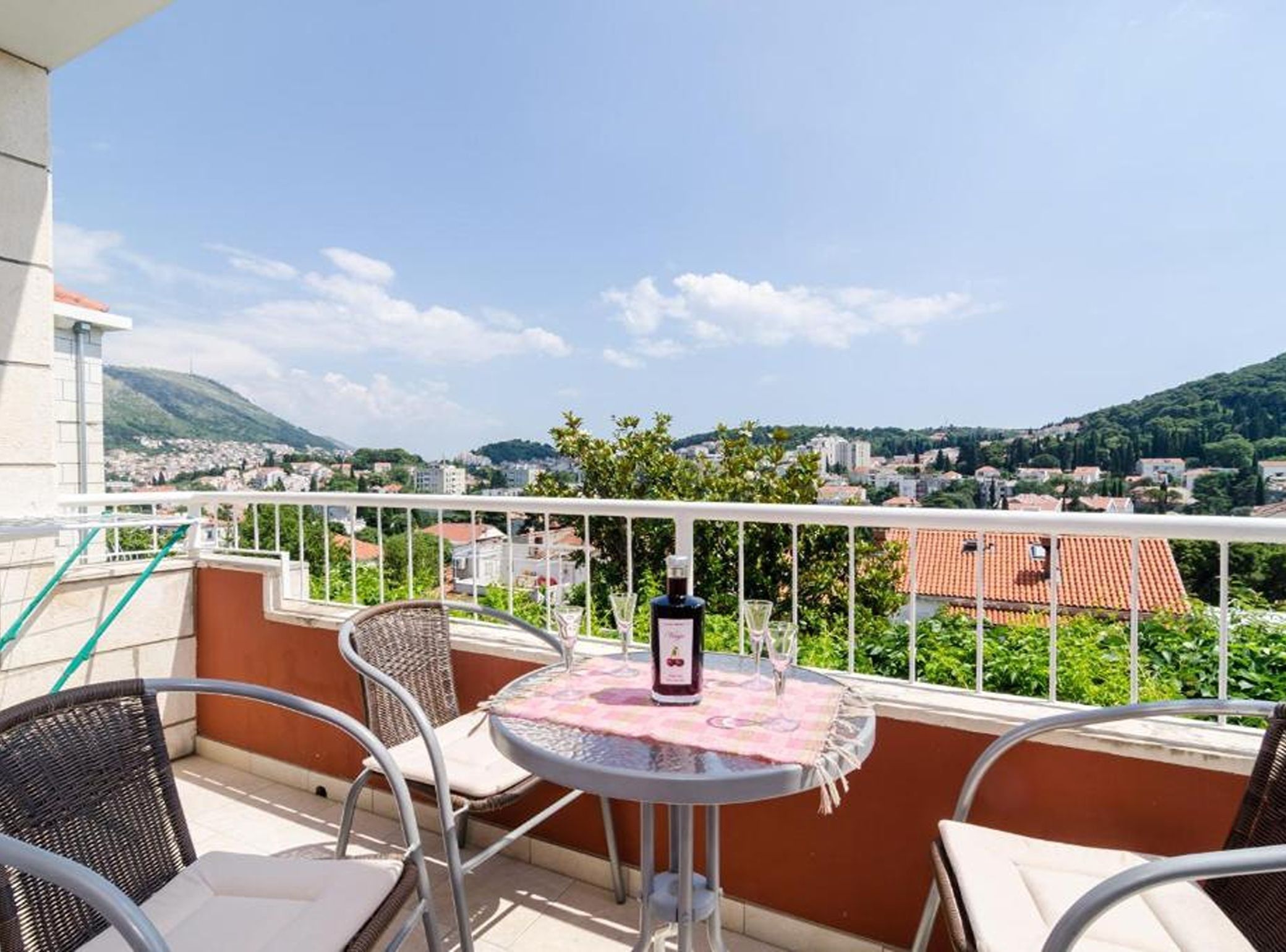Un balcon avec une table, des chaises et une bouteille de vin.