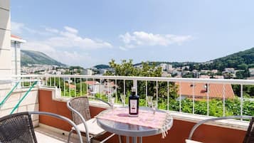 Un balcon avec une table, des chaises et une bouteille de vin.