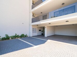 A multi-level building with a flat roof, a covered outdoor area, and a paved entrance. - Double Bedroom Apartment with Terrace (Dubrovnik)