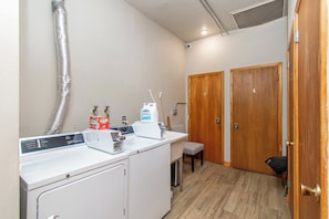A compact kitchen with a washing machine, a small table, and two wooden doors. - 1BR I Second Story on Main #2, Walk to DT, Queen (Fargo)