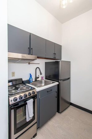 A compact kitchen with a stove, sink, and refrigerator. - 1BR I Second Story on Main #2, Walk to DT, Queen (Fargo)