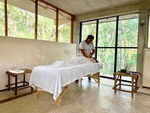 Una habitación con cama, ventana y una pequeña mesa con objetos encima.