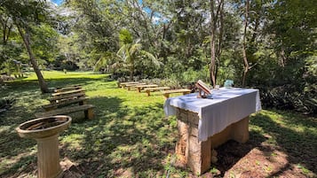 An outdoor area with stone benches, a table with a tablecloth, and a bird bath.