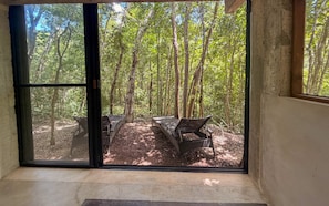 Habitació amb un gran finestral corredís que dona a una zona exterior amb una panxa i un hamaca.