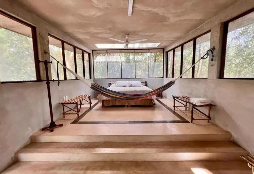 Quarto com cama, rede e escada para uma varanda.