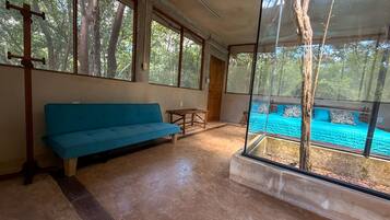 A room with a blue sofa, a wooden bench, and a bed with a blue bedspread.