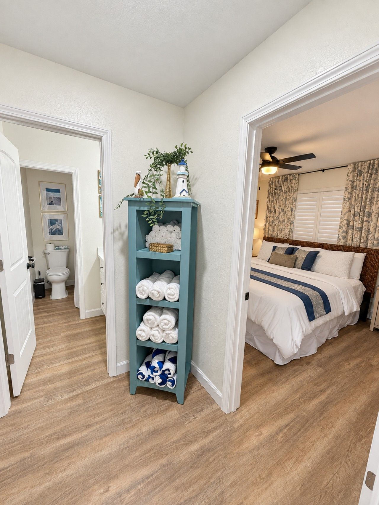 Ein Schlafzimmer mit einem Bett, einem Handtuchregal und Blick ins Badezimmer.