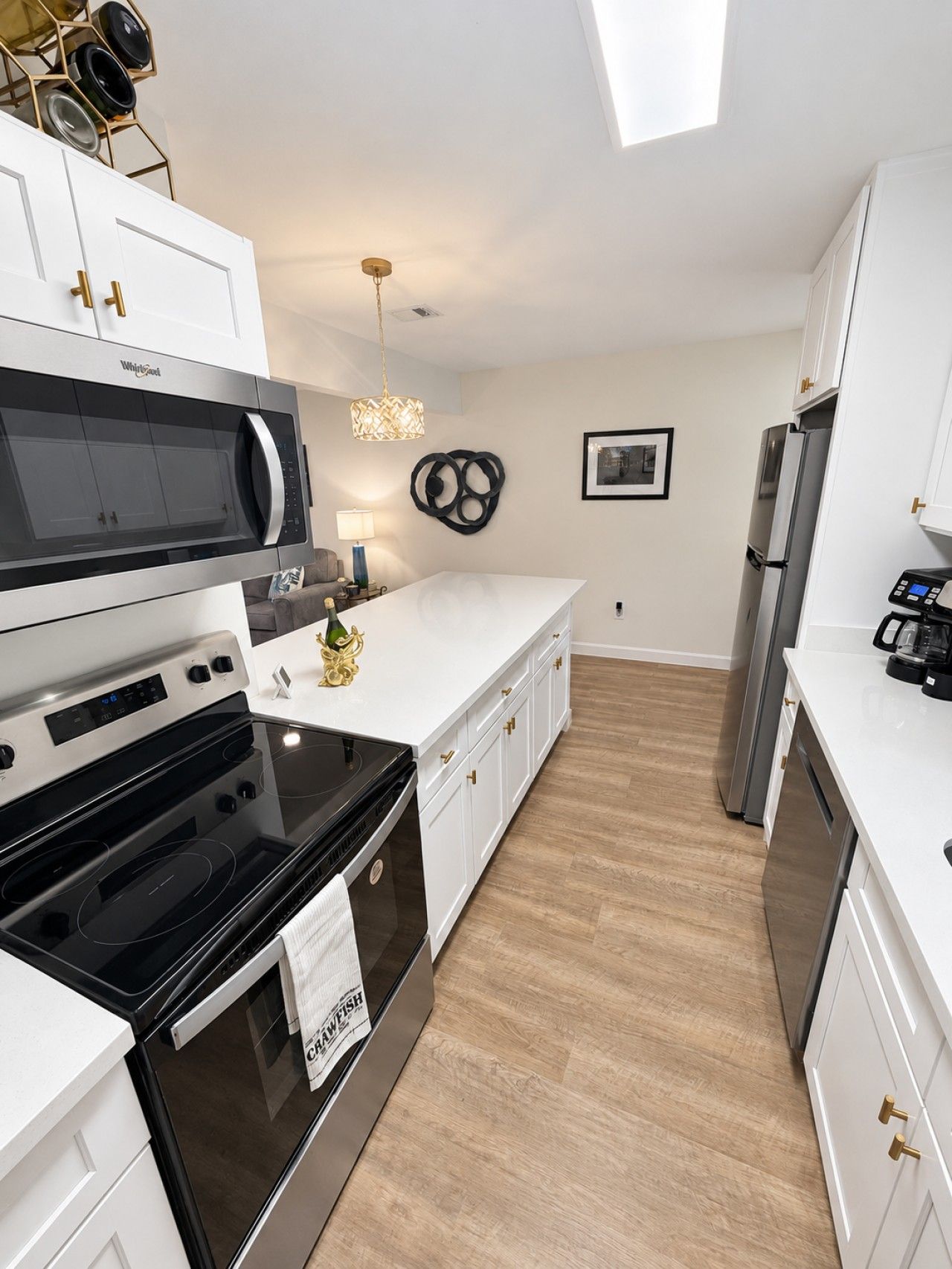 A modern kitchen with white cabinetry, a black stove, a microwave, and a refrigerator.