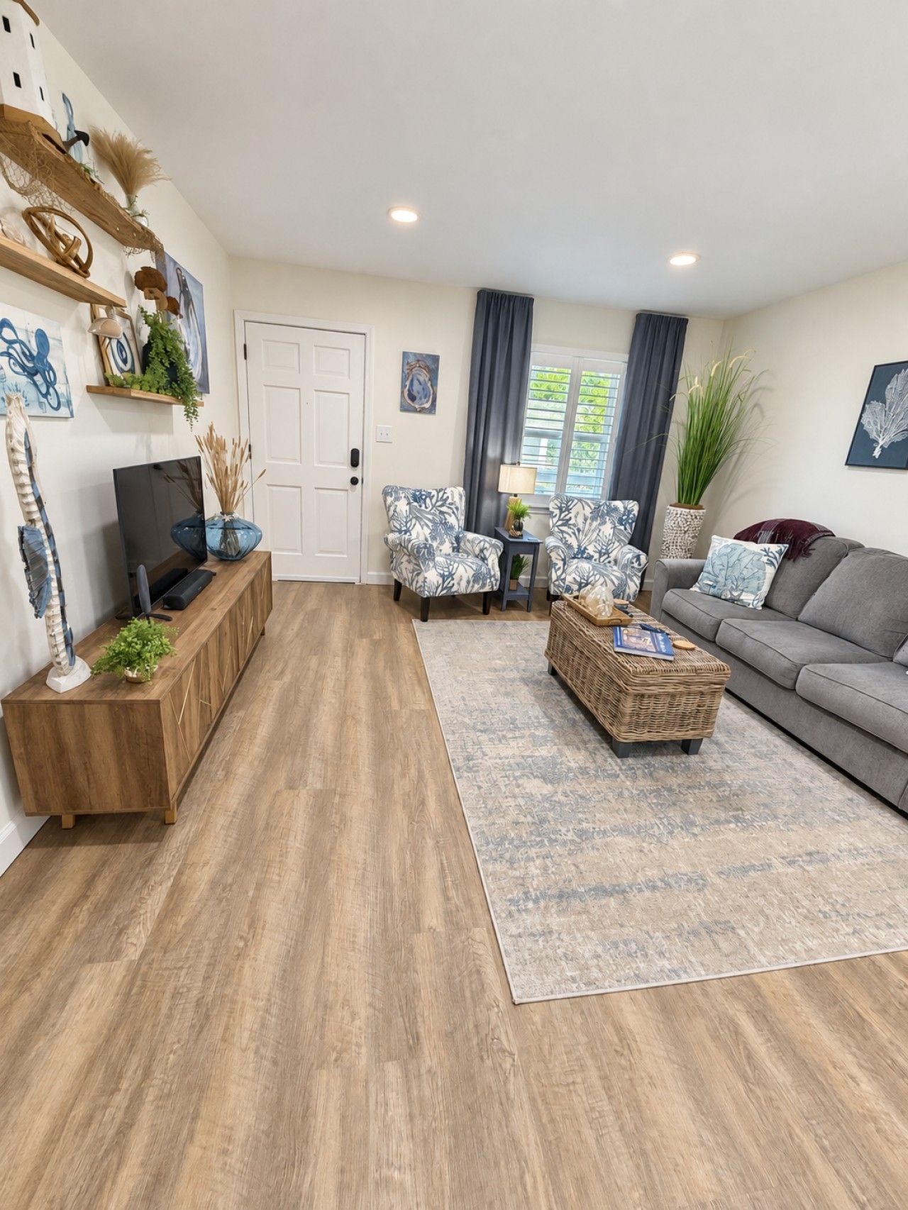 A living room with a sofa, two armchairs, a coffee table, and a TV on a wooden cabinet.
