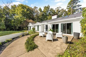 Et moderne hus med terrasse, hvid facade og store vinduer.