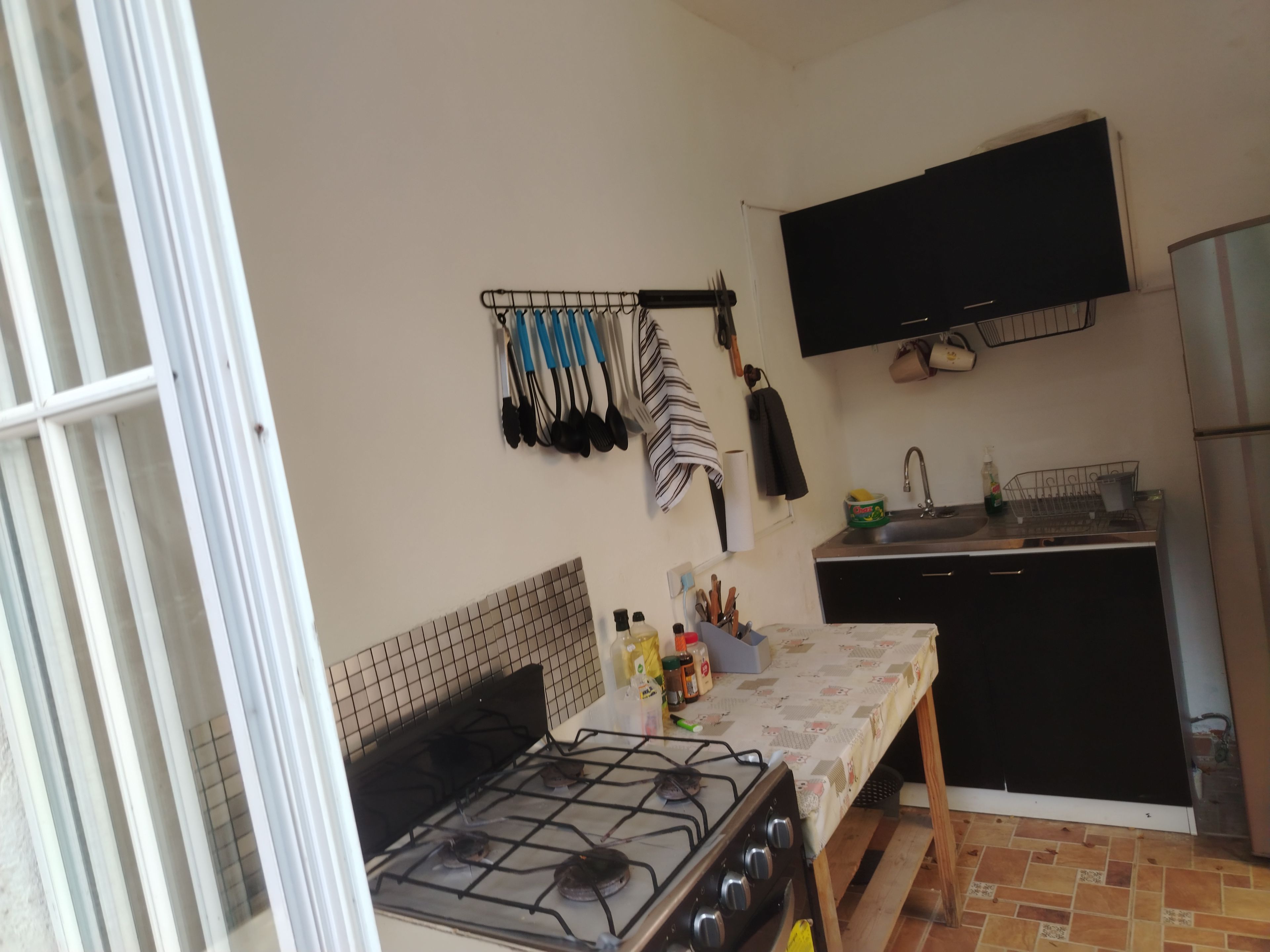 Una cocina compacta con estufa a gas, un lavamanos y un mueble negro.