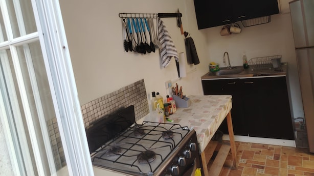 Una cocina compacta con estufa a gas, un lavamanos y un mueble negro.