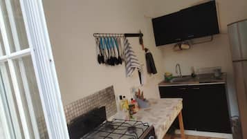 Una cocina compacta con estufa a gas, un lavamanos y un mueble negro.