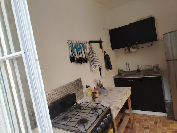 Une cuisine de taille réduite, équipée d’une cuisinière à gaz, d’un évier et d’un meuble noir.