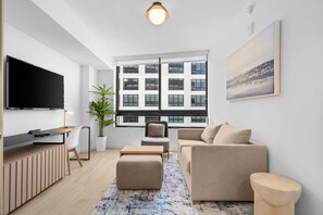 Ein modernes Wohnzimmer mit Flachbildfernseher, einer Couch, einem Couchtisch und einem großen Fenster mit Blick auf die Stadt.