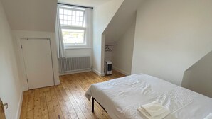 A bedroom with a single bed, wooden flooring, a radiator, a window, and a door. - Nice London flat with free private parking and 20 min train to central London (Bromley)