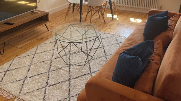 A living room with a TV, a round glass coffee table, a sofa, and a dining table with chairs. - Nice London flat with free private parking and 20 min train to central London (Bromley)