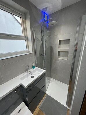 Ein modernes Badezimmer mit Dusche, Fenster und Waschbecken.