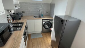 A compact kitchen with a built-in washing machine, a refrigerator, and a skylight. - Nice London flat with free private parking and 20 min train to central London (Bromley)