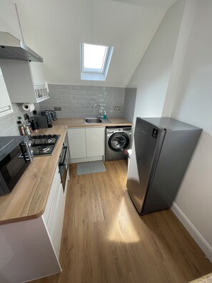 Eine kompakte Küche mit Einbauwaschmaschine, Kühlschrank und Dachfenster.